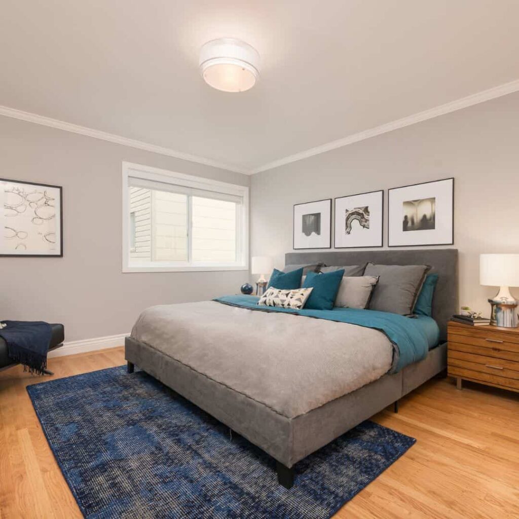 Grey wall with teal bedding and gray bed frame